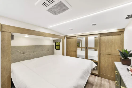 Spacious bedroom inside the 2025 Heartland Eddie Bauer 3100RL, featuring a comfortable king-size bed, stylish overhead storage, and modern decor.