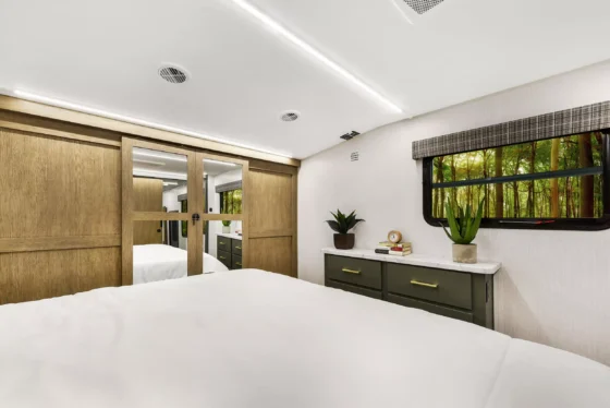 Spacious bedroom inside the 2024 Heartland Eddie Bauer 3100RL, featuring a king-size bed, overhead storage, and modern décor.
