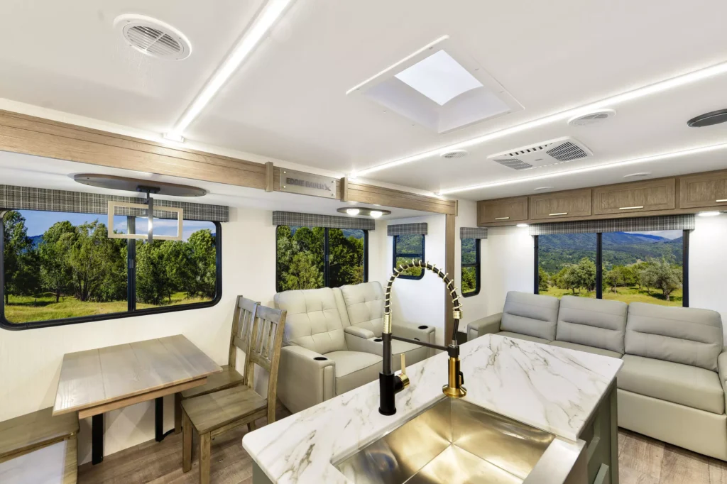 Dining table, two couches, countertops, and sink in the 2025 Eddie Bauer CWEL 3311RL RV living area.