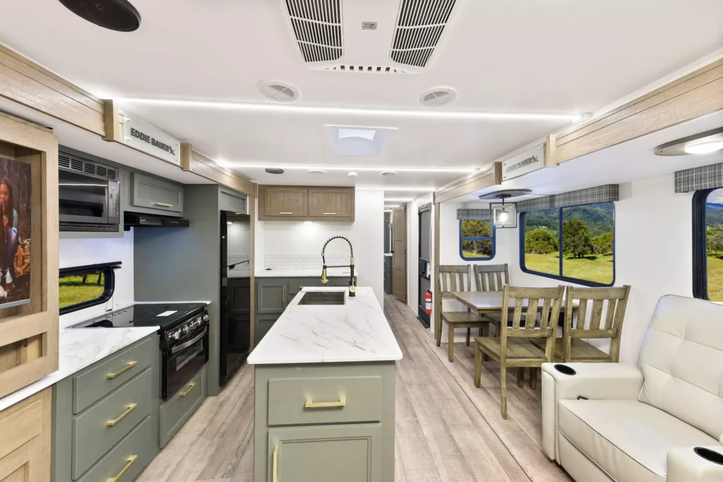 Kitchen area in the 2025 Eddie Bauer CWEL 3311RL RV, featuring a modern countertop, sink, and a dining table.