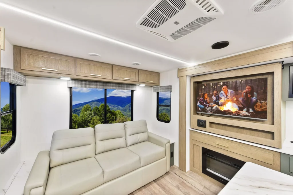 Cozy living room in the 2025 Eddie Bauer CWEL 3311RL RV, featuring a comfortable sofa, fireplace, and TV setup.