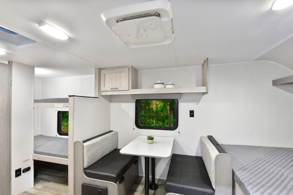 The image showcases the exterior of the 2025 Prowler P17B travel trailer, highlighting its sleek and modern design. The trailer features a streamlined silhouette with a distinctive front profile, complemented by eye-catching graphics that enhance its appeal. Large windows allow for plenty of natural light and provide an inviting atmosphere. The sturdy entry steps lead to a spacious and well-equipped interior, perfect for adventurers seeking comfort on the road. This travel trailer balances style and functionality, making it an excellent choice for camping trips and family outings.